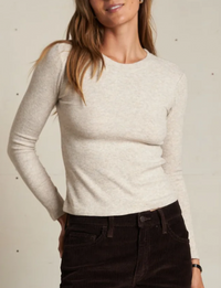 Woman wearing a beige long-sleeve top against a neutral background